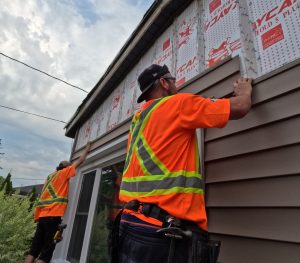 Image of two Aurora Exteriors Inc Contractors installing siding on a residential home in Chatham Ontario on Faubert Drive.