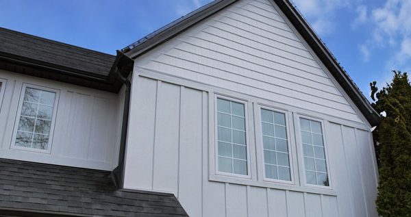 Image of a Modern Farmhouse style home with white board and batten siding with Windows installed by Aurora Exteriors Inc with white trim.
