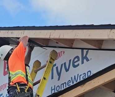 Image of an Aurora Exteriors Inc employee affixing black vented aluminum soffit material to a new construction home.