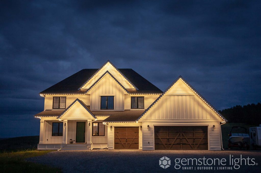 White farmhouse style home with Gemstone Permanent Holiday Lighting installed, displaying a true warm white.