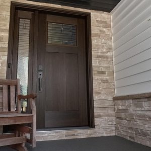 Image showing stone siding applied by Aurora Exteriors Inc to create an entry way accent around the exterior door, in a mission point colour.