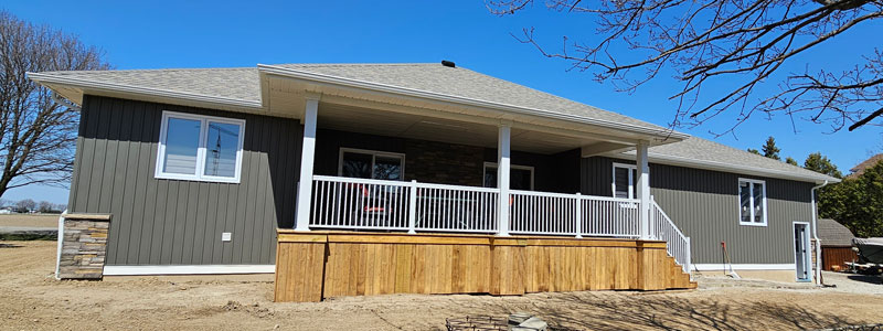 Image of a pressure treated wood covered deck with stunning white aluminum railings and matching white aluminum post wraps constructed by deck contractors Aurora Exteriors Inc.